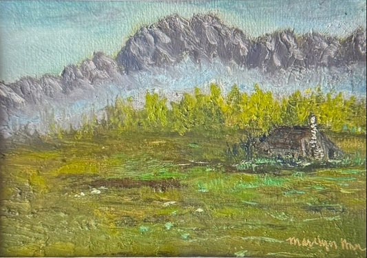 A framed landscape painting displayed on a laptop screen. The painting depicts a green field with yellow wildflowers, a small cabin, and gray mountains under a blue sky.