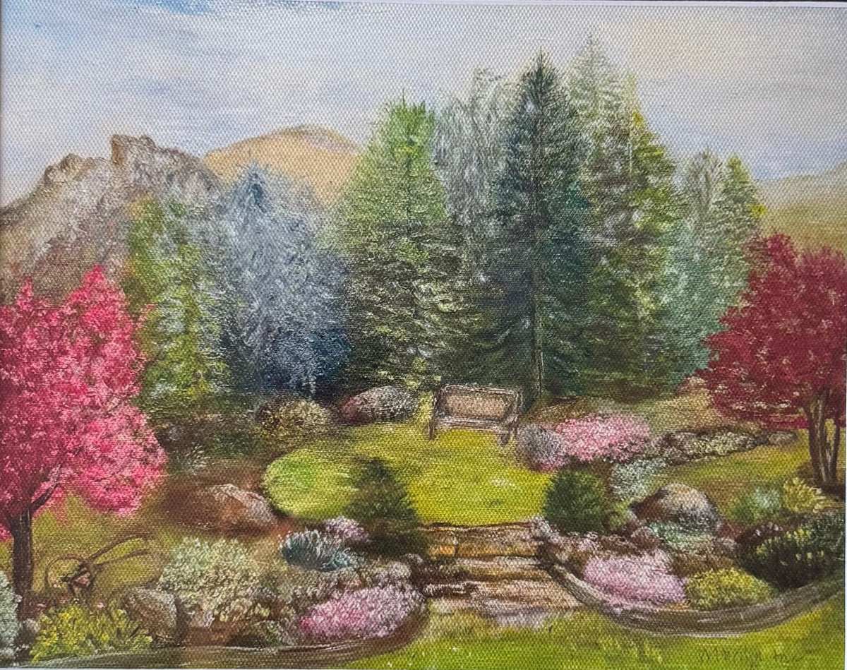 A framed landscape painting depicting a lush garden with pink and red trees, green grass, and distant hills under a pale sky, set in a white mat and a dark wood frame.