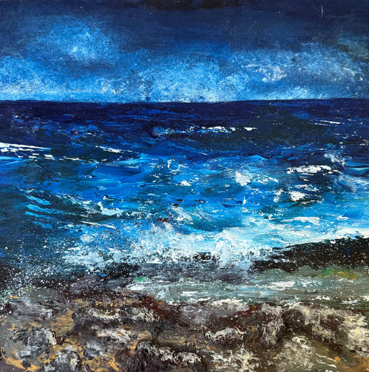 A square framed painting of a dramatic blue ocean scene with white waves crashing onto a rocky shore, displayed on a rustic wooden surface.